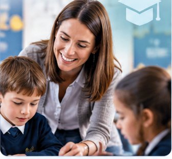 A teacher leaning over a desk in a classroom, helping two primary school children with their work.